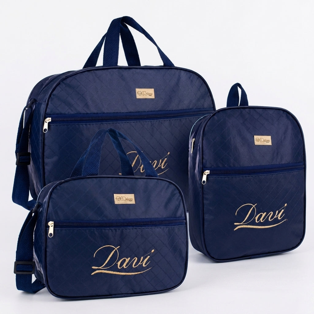 Três bolsas de maternidade azul-marinho personalizadas em dourado posicionadas sobre fundo branco.