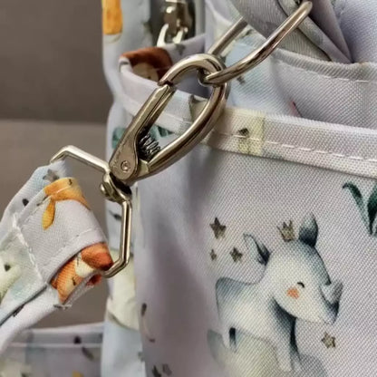 Detalhe aproximado do fecho metálico prateado na alça da bolsa cinza com estampa safari
