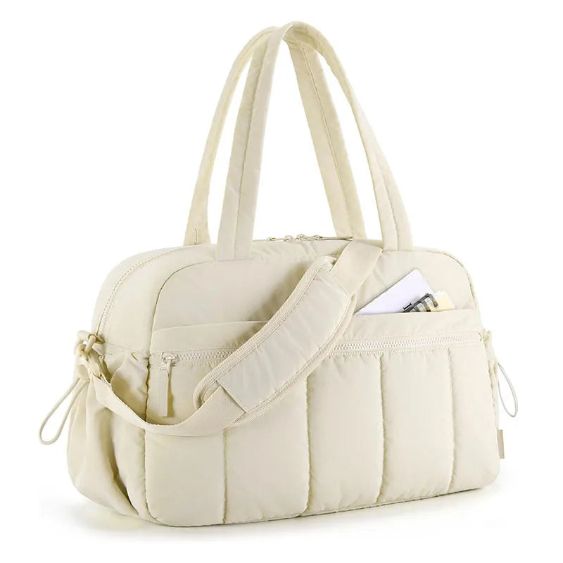 Bolsa acolchoada cor creme em vista diagonal com alça transversal e de mão.