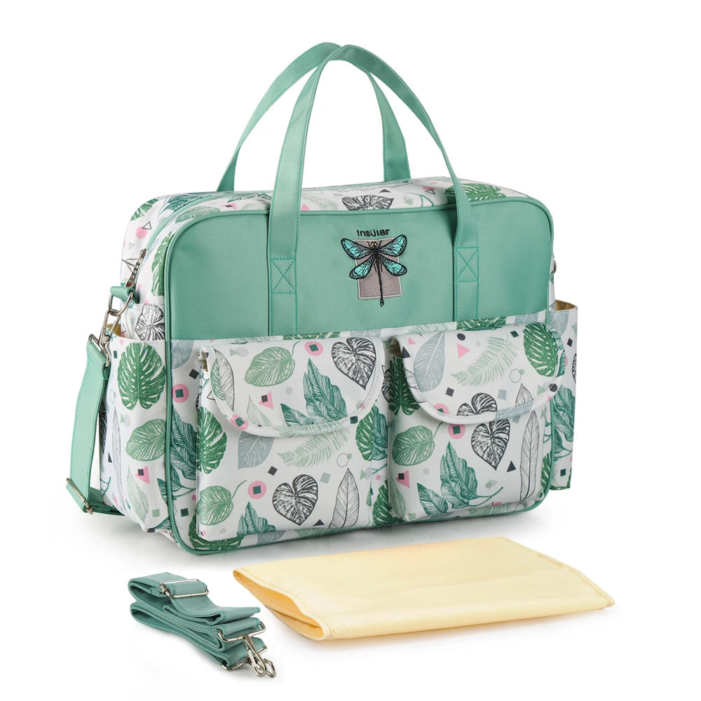 Bolsa retangular verde e branca com estampa tropical, fotografada de ângulo com trocador amarelo.