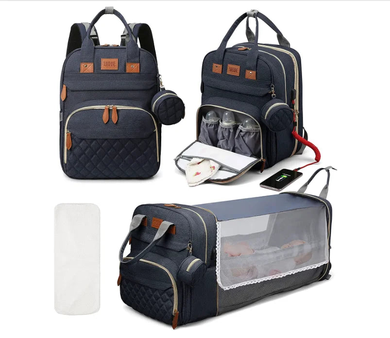 Mochila maternidade azul-marinho mostrada fechada, aberta com mamadeiras e estendida como berço portátil.