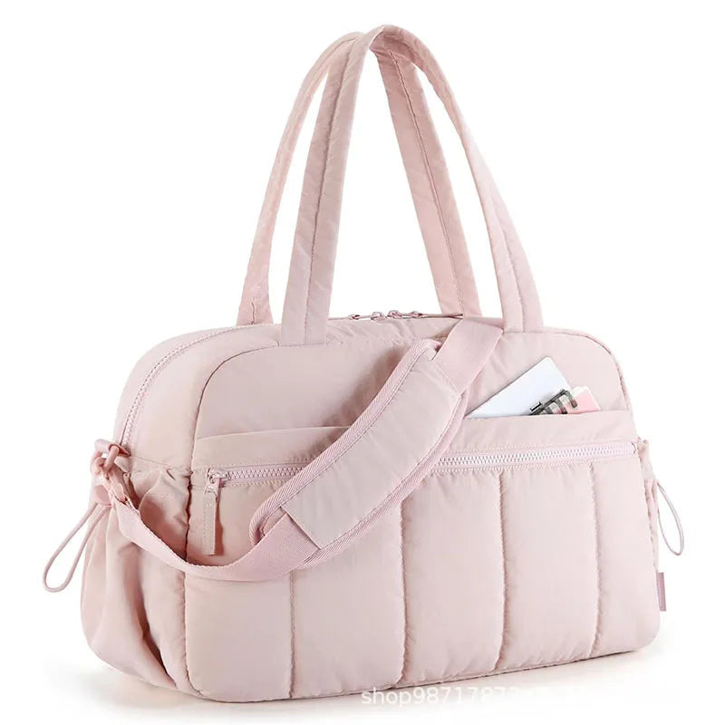 Bolsa acolchoada rosa-claro com alças, exibida em ângulo de três quartos.