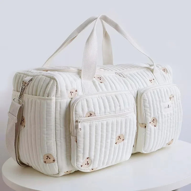 Bolsa maternidade branca acolchoada com ursinhos bordados, vista em ângulo de três quartos.