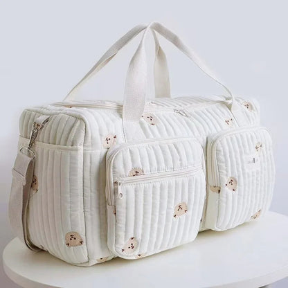 Bolsa maternidade branca acolchoada com ursinhos bordados, vista em ângulo de três quartos.