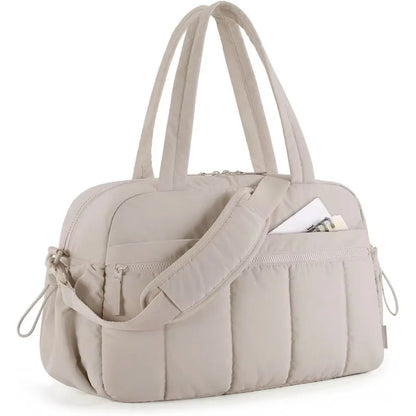 Bolsa acolchoada bege claro vista de lado, com alças de mão e de ombro.