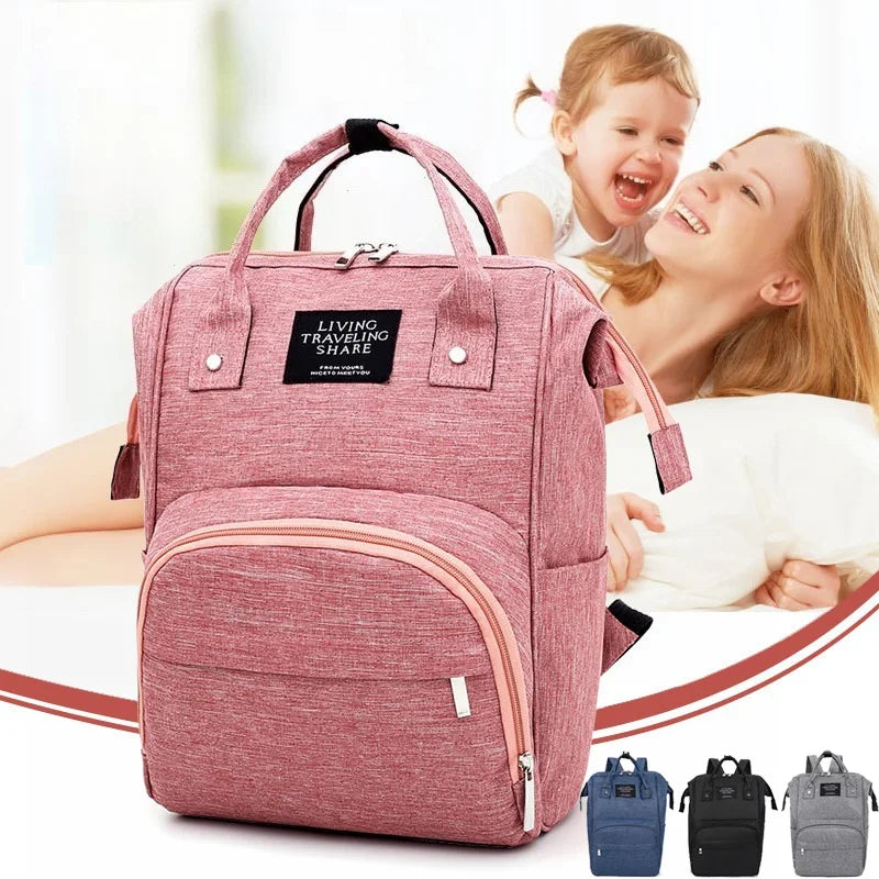 Mochila maternidade rosa-salmão de formato estruturado, exibida em ângulo frontal com alças superiores.
