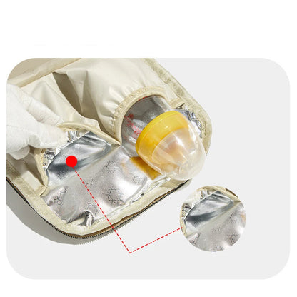 Detalhe interno de bolsa bege mostrando bolso térmico prateado com mamadeira amarela.