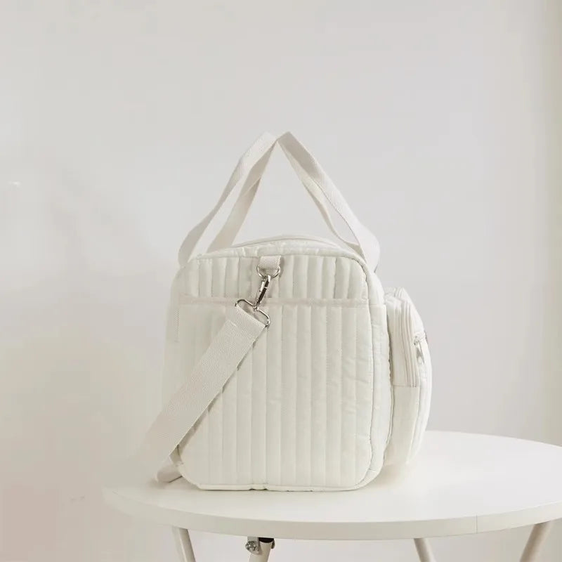 Bolsa transversal acolchoada branca em vista lateral sobre uma mesa redonda.