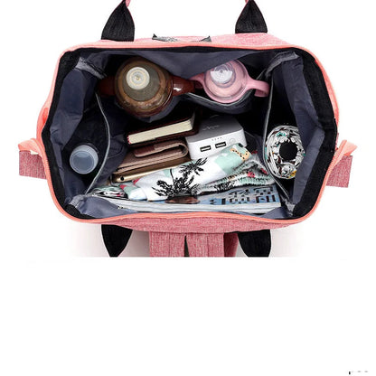 Vista aérea de mochila rosa aberta revelando o interior cinza organizado com diversos objetos.