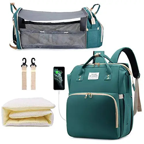 Mochila maternidade verde, berço portátil aberto, trocador dobrado e acessórios em fundo branco.