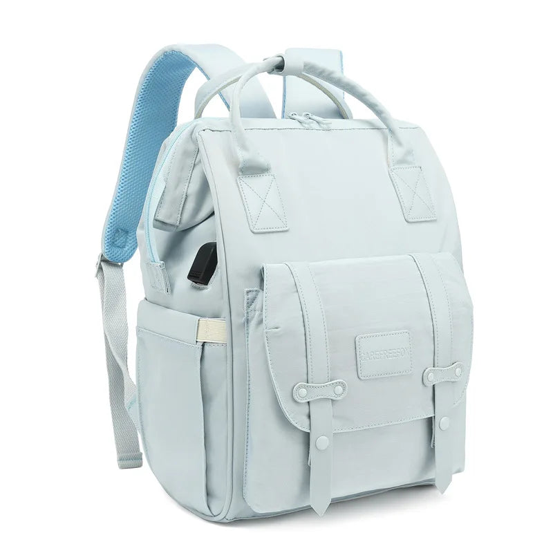 Mochila de maternidade azul-clara em ângulo de três quartos contra fundo branco.
