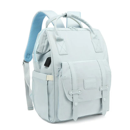 Mochila de maternidade azul-clara em ângulo de três quartos contra fundo branco.