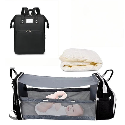 Mochila preta fechada, colchonete dobrado e berço portátil cinza aberto vista frontal.