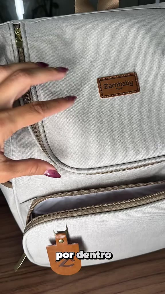 Visão aproximada de mochila de maternidade bege em linho com detalhes em couro marrom.