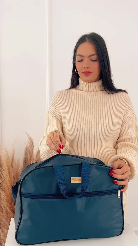 Bolsa maternidade azul estruturada com bolso frontal, alças de mão e logotipo dourado.