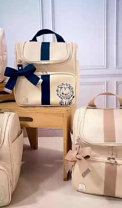 Mochila de maternidade bege com listra azul, laço e bordado vista de frente.