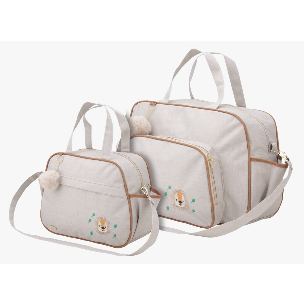 Duas bolsas de maternidade beges com detalhes marrons, bordado de leão e chaveiros pompom.