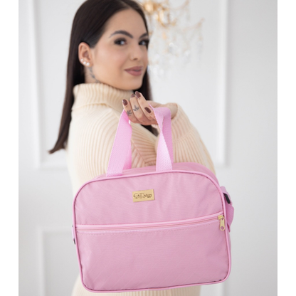 Bolsa maternidade rosa claro, formato retangular com alça curta e bolso de zíper frontal.
