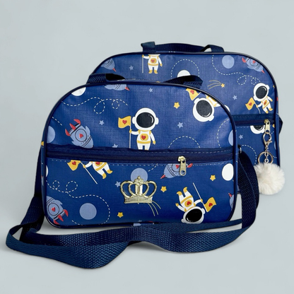Duas bolsas de maternidade azuis com estampa espacial, coroa dourada e chaveiro de pompom.