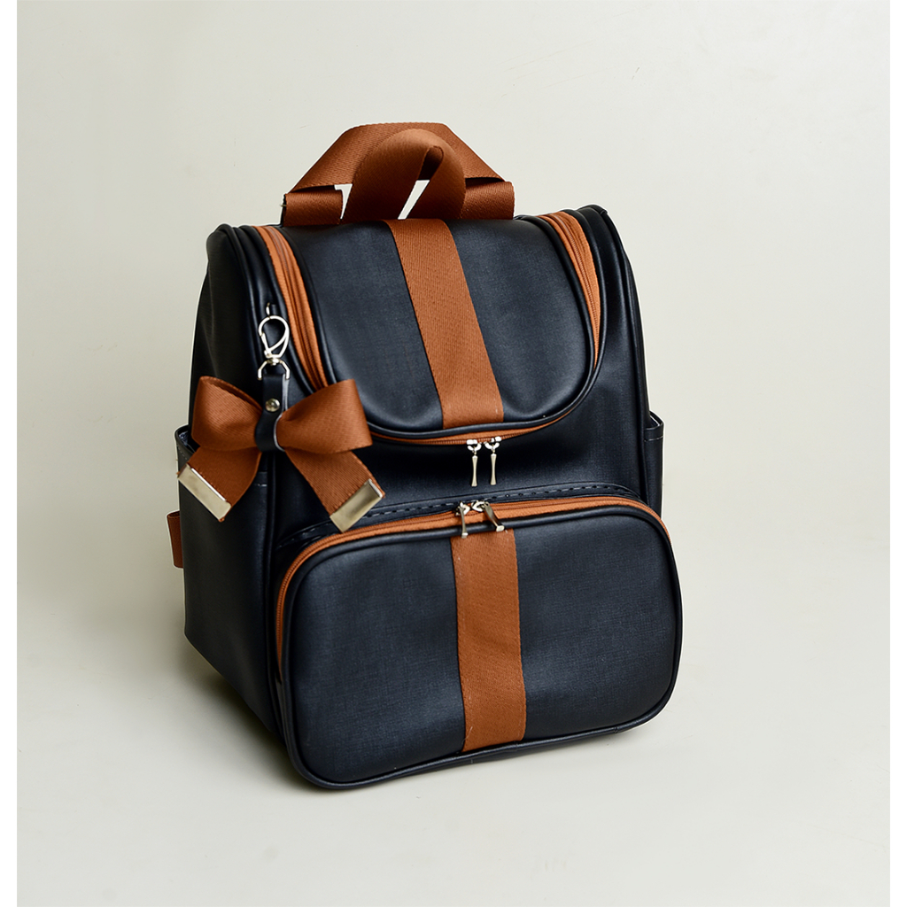 Mochila preta com listras marrons e laço, fotografada em ângulo de três quartos.