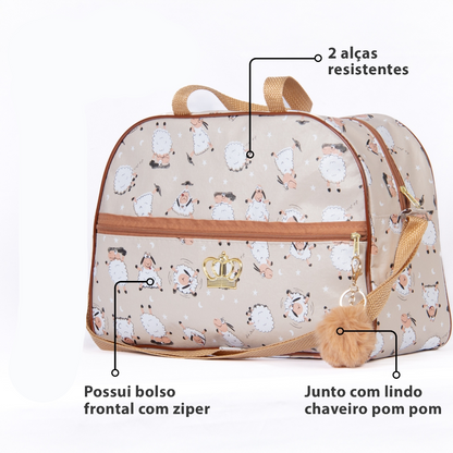 Bolsa de maternidade bege estampada com ovelhinhas e chaveiro pompom em fundo branco.