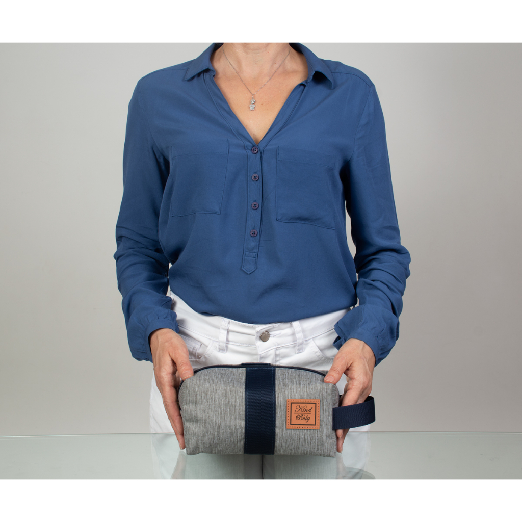 Mulher segurando necessaire retangular cinza e azul com etiqueta marrom, em vista frontal.