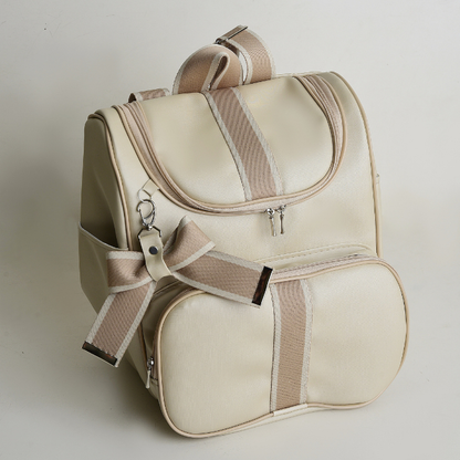 Mochila maternidade bege estruturada com detalhes listrados marrons e laço pendurado, vista diagonal.