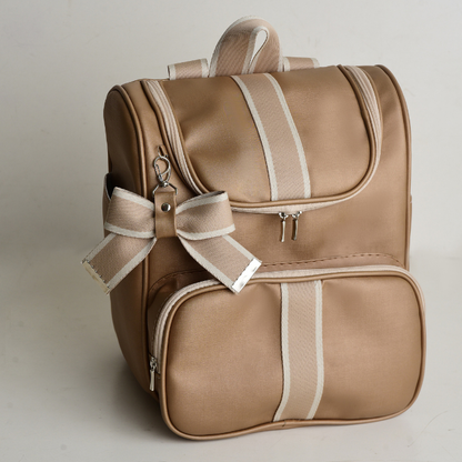 Mochila de maternidade caramelo com listras claras, laço decorativo, vista em ângulo diagonal.