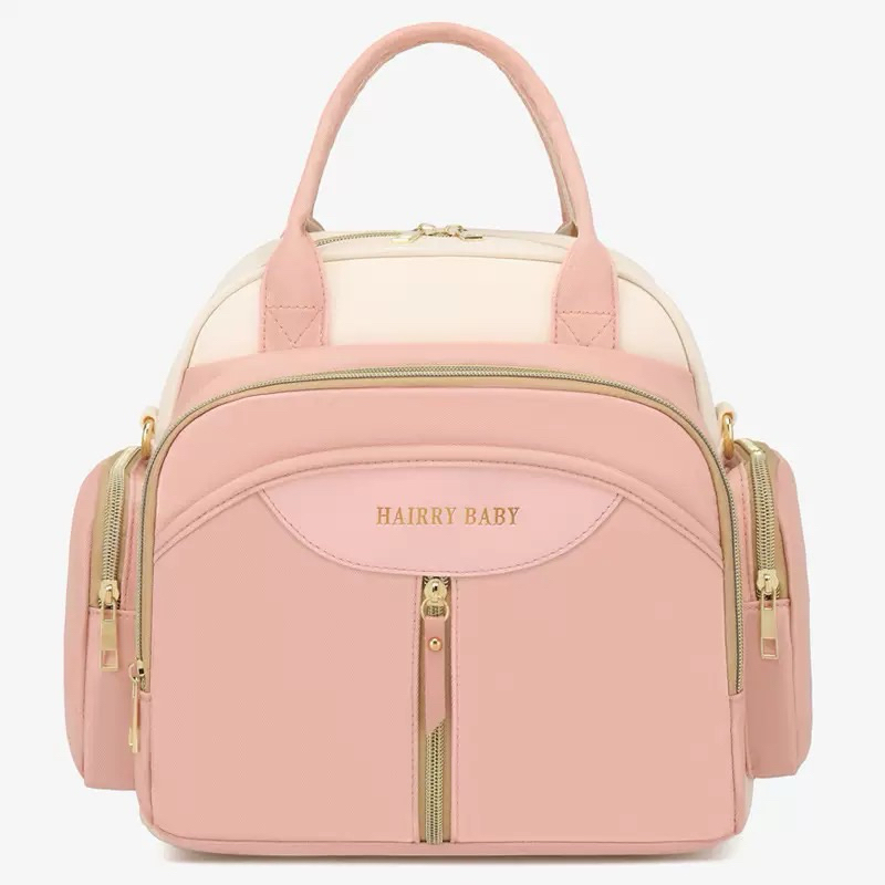 Vista frontal de bolsa maternidade rosa e creme com alças e zíperes dourados.