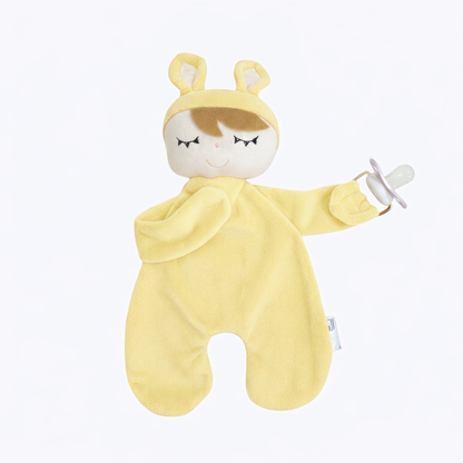 Naninha amarela macia com carinha de boneco dormindo e prendedor segurando uma chupeta.