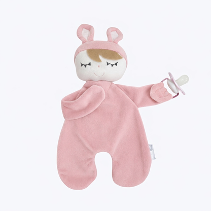 Naninha de pelúcia rosa com orelhas de coelho segurando chupeta em fundo branco.