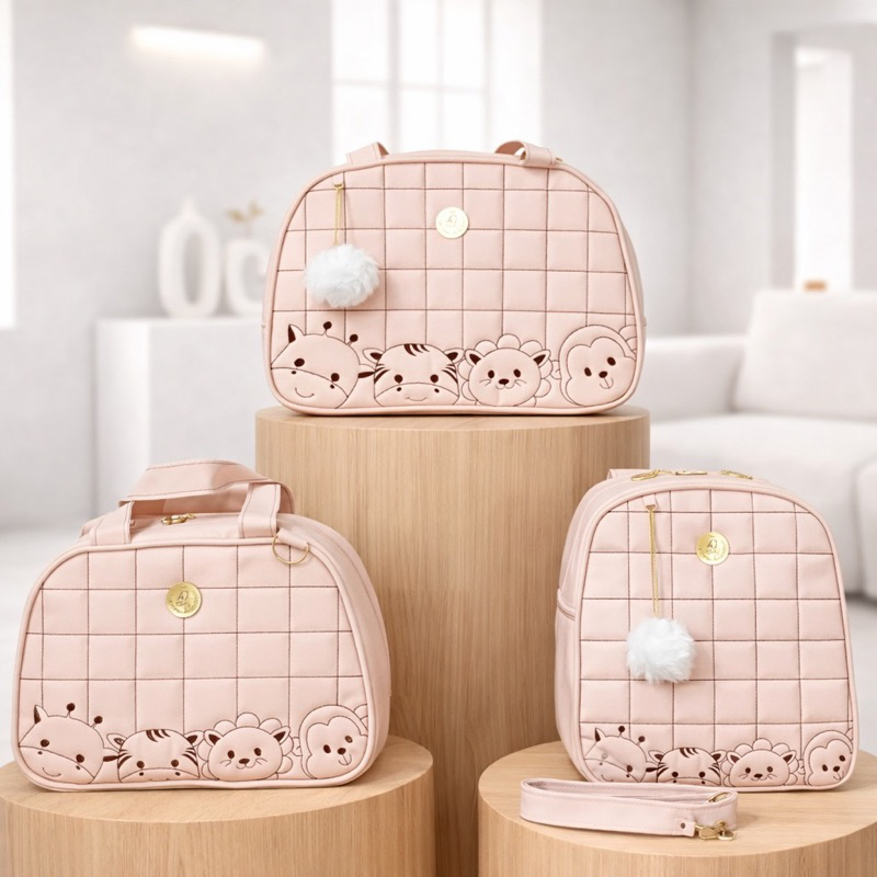 Três bolsas de maternidade rosa claro com desenhos de animais em pedestais de madeira.