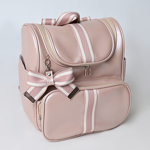 Mochila maternidade rosa estruturada com laço listrado, em ângulo diagonal sobre fundo claro.