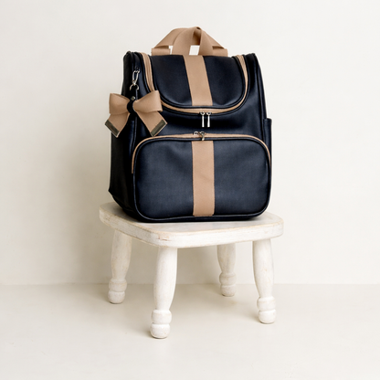 Vista frontal de mochila preta e bege sobre banquinho de madeira branco.