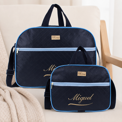 Duas bolsas maternidade azul-marinho com detalhes azuis-claros e bordado dourado, de frente.