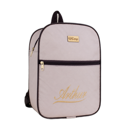 Mochila lilás-claro com nome Arthur bordado em dourado, vista de frente sobre mesa.