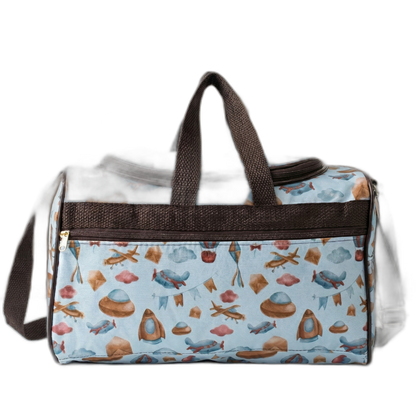 Bolsa de maternidade azul com estampas de aviação e alças marrons, em vista frontal.