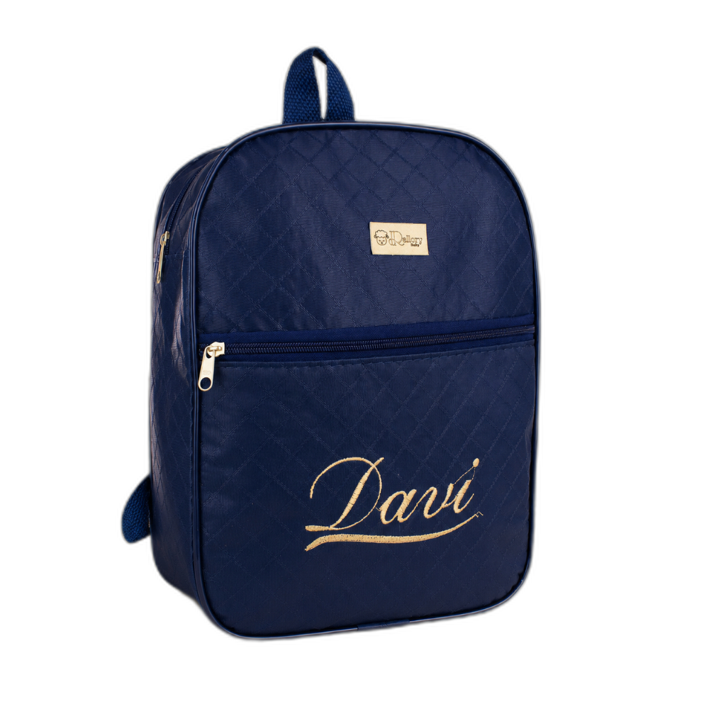 Mochila azul-marinho com bordado dourado Davi em uma superfície de madeira clara.