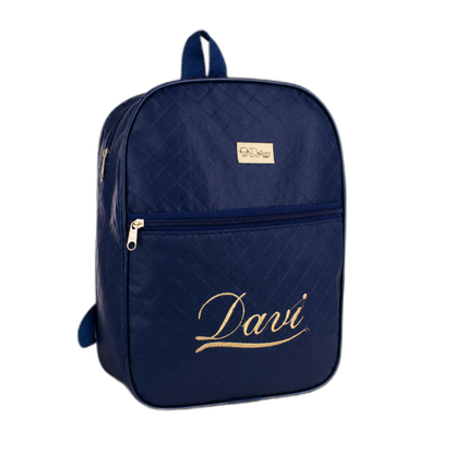 Mochila azul-marinho com bordado dourado Davi em uma superfície de madeira clara.