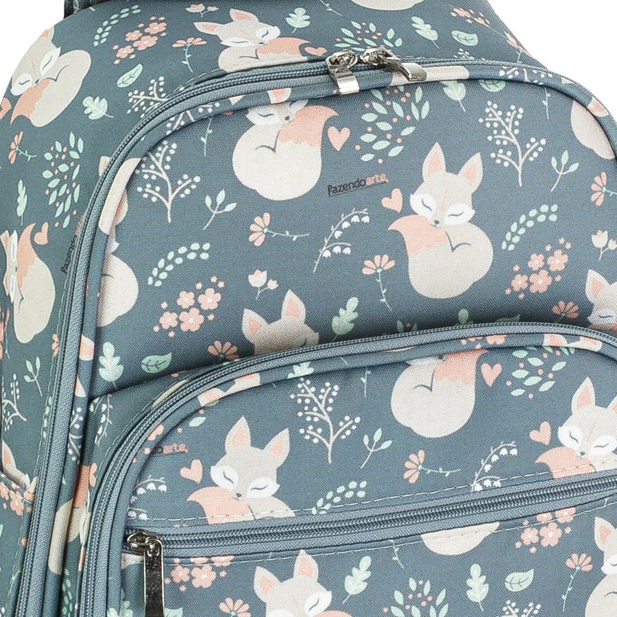 Detalhe em close-up de mochila cinza-azulada com estampa de raposas e zíperes prateados.