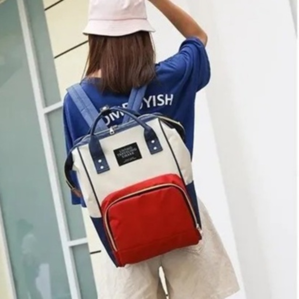 Mochila de maternidade tricolor em azul, bege e vermelho, vista de costas.