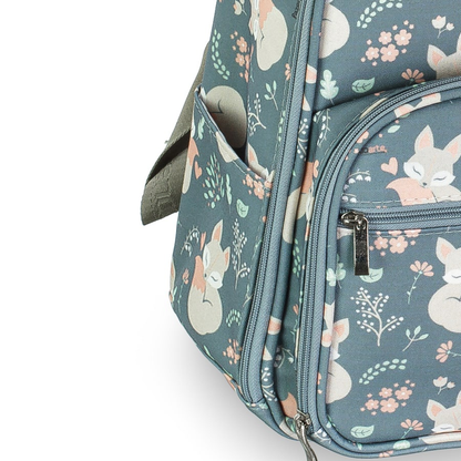 Close-up lateral de mochila verde-azulada com estampa de raposas, bolso e zíperes.