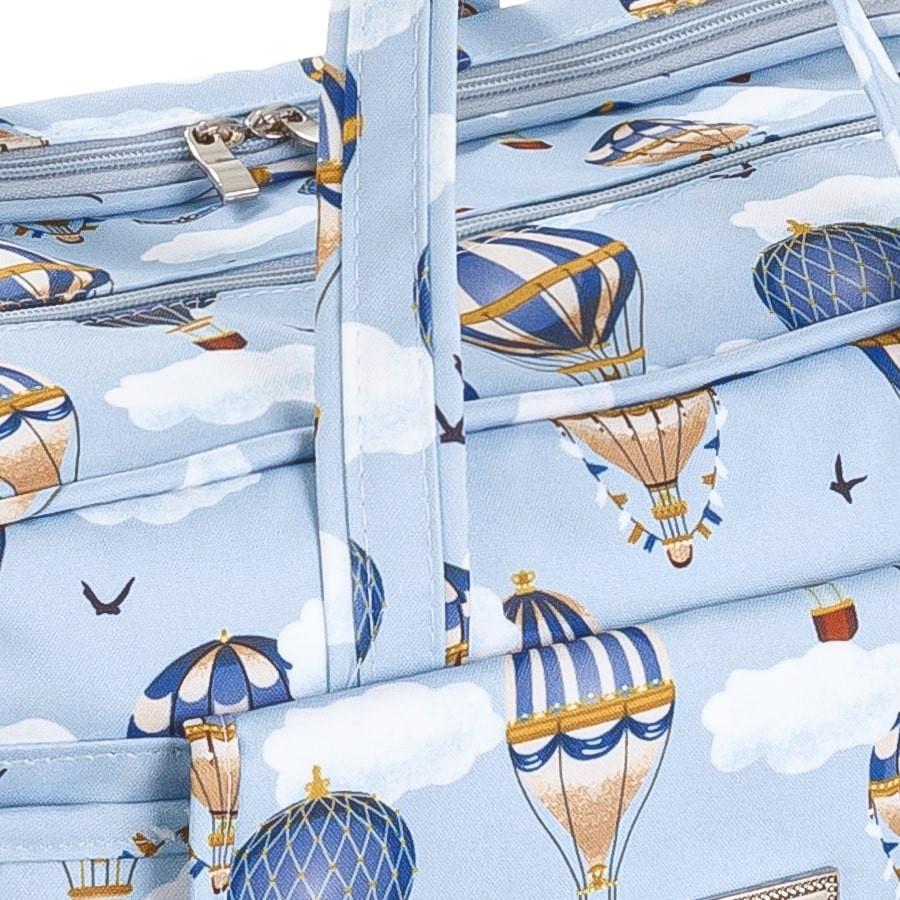 Detalhe em close-up de bolsa azul com estampa de balões e nuvens