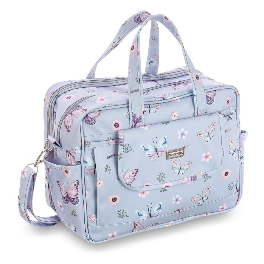 Bolsa de maternidade azul com estampa de borboletas e flores em perspectiva diagonal.