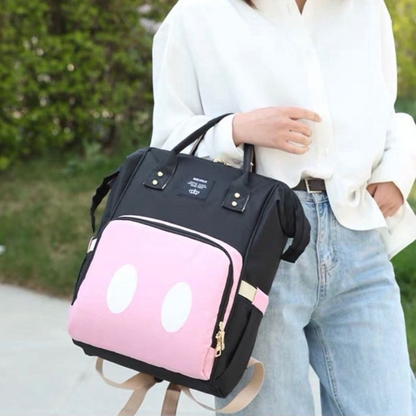 Mochila preta e rosa com detalhes ovais brancos, formato estruturado e alças creme.