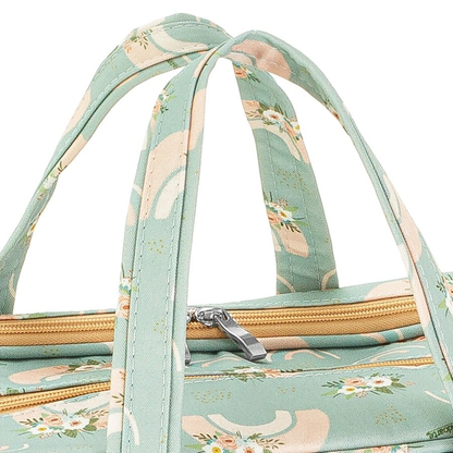 Detalhe das alças e zíper de bolsa maternidade verde-clara com estampa floral.