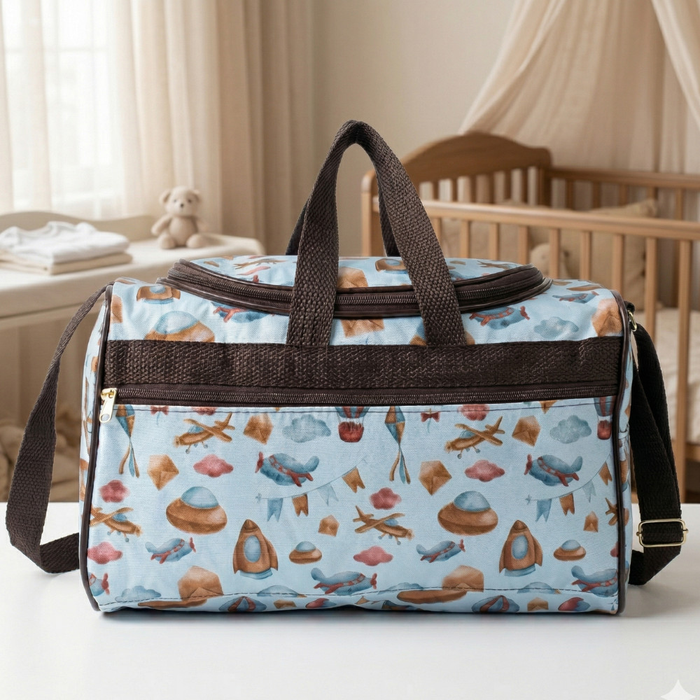 Bolsa maternidade azul-claro com estampas e alças marrons, fotografada de frente sobre mesa branca.