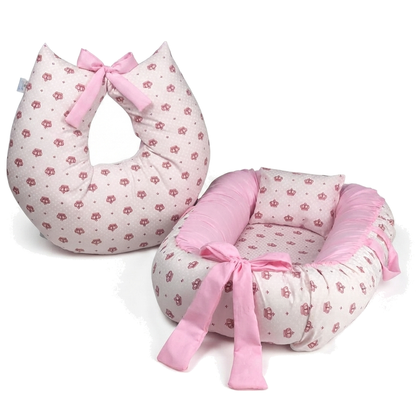 Almofada de amamentação e ninho de bebê rosa com estampa de coroas e laços.